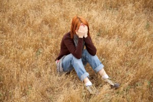 Lonely sad red-haired girl at field