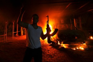 A protester reacts as the U.S. Consulate in Benghazi is seen in flames during a protest by an armed group said to have been protesting a film being produced in the United States in this September 11, 2012 file photo. Ahmed Abu Khatallah, a key suspect in the 2012 attack on the U.S. diplomatic compound in Benghazi, Libya, is being held on a U.S. ship following his capture over the weekend by U.S. special operations forces, a U.S. official said on June 17, 2014. The official, speaking on condition of anonymity, said the suspect was apprehended on the outskirts of Benghazi in a secret operation. He will be brought to the United States, the official added. REUTERS/Esam Al-Fetori/Files (LIBYA - Tags: POLITICS CIVIL UNREST)